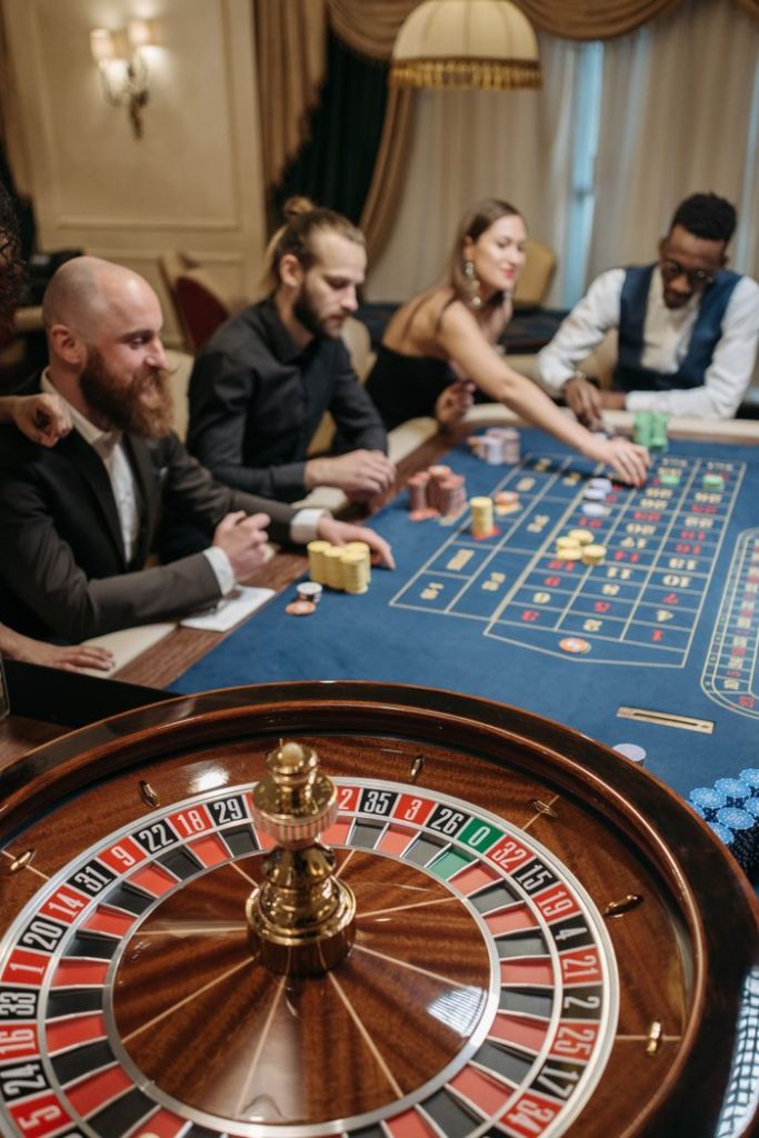 Group of diverse people enjoying a thrilling game of roulette in a luxurious casino setting.
